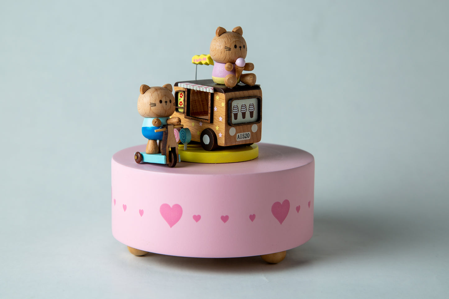 Toy truck with teddy bear figures on a pink base with heart patterns against a light blue background