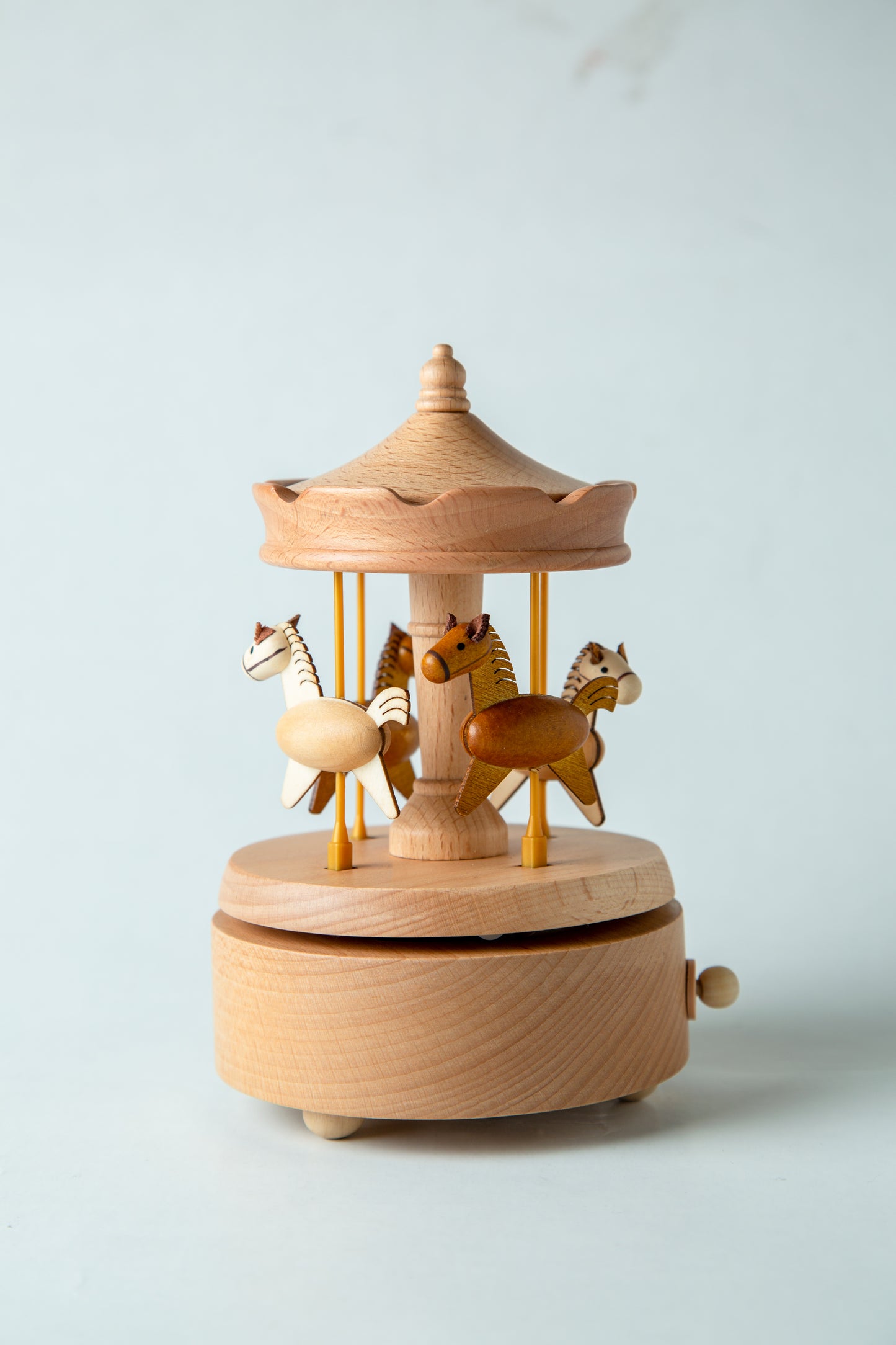 Wooden carousel toy with horses on a light gray background
