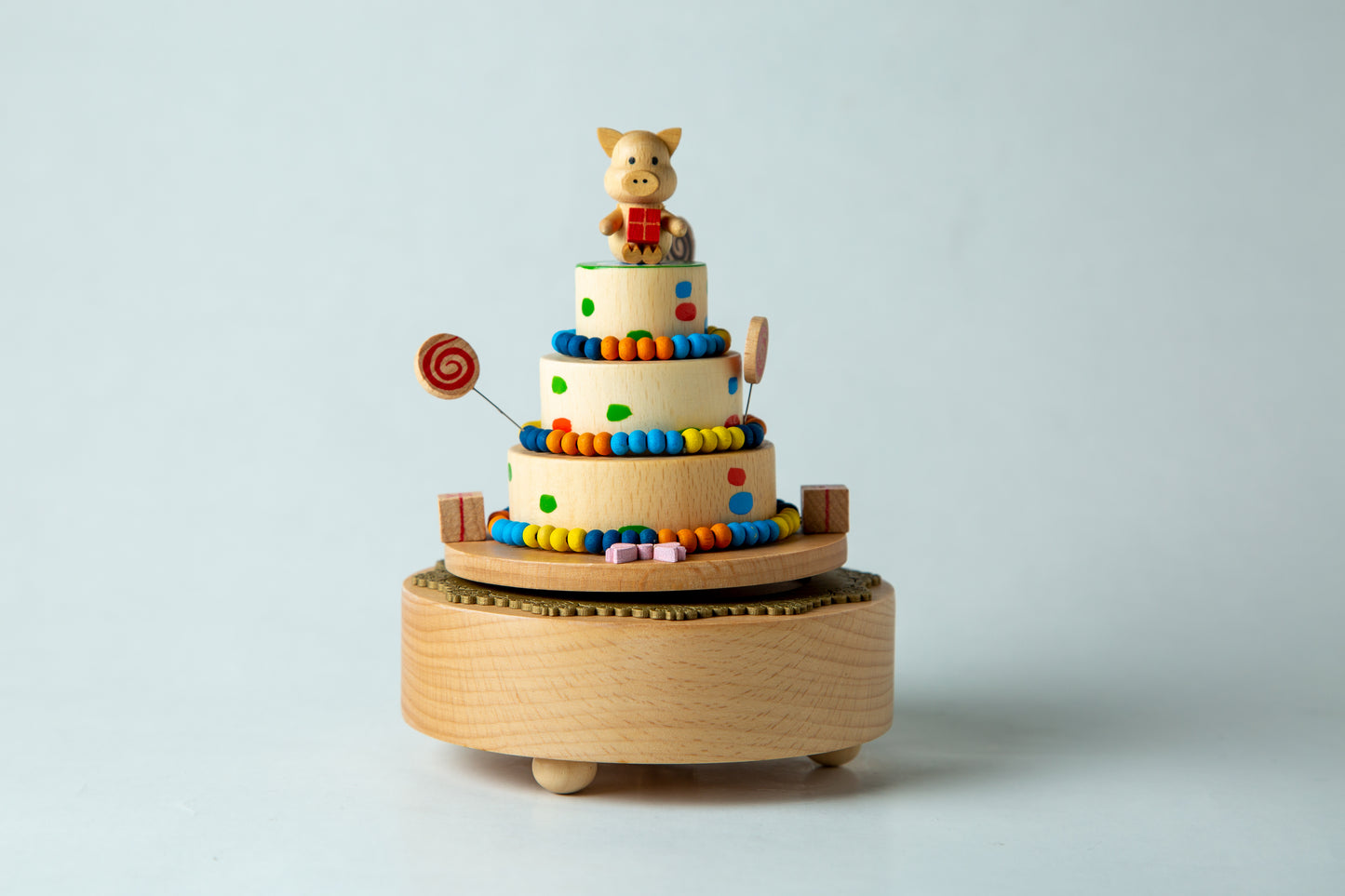 Wooden toy with colorful layers and a figurine on top against a light gray background