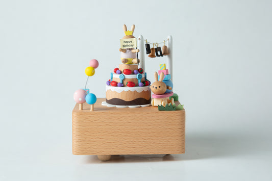 Wooden music box with a cake and rabbit design on a white background