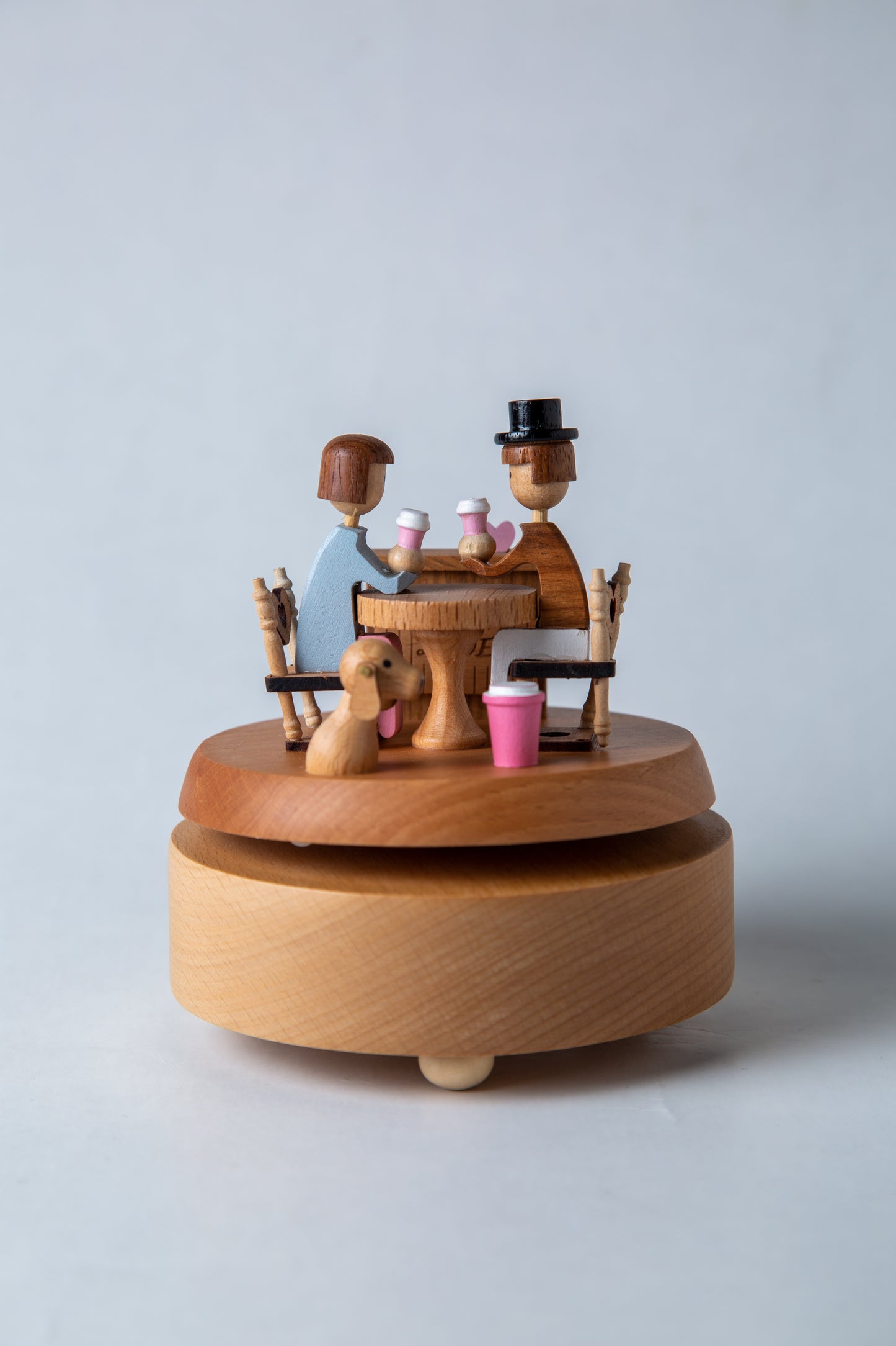 Wooden music box with a couple and dog at a table on a light gray background