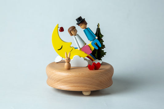 Decorative wooden figurine with a couple on a moon, rabbit, and Christmas tree on a light gray background